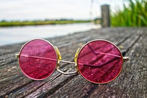 pink metal sunglasses lying upside down on boardwalk